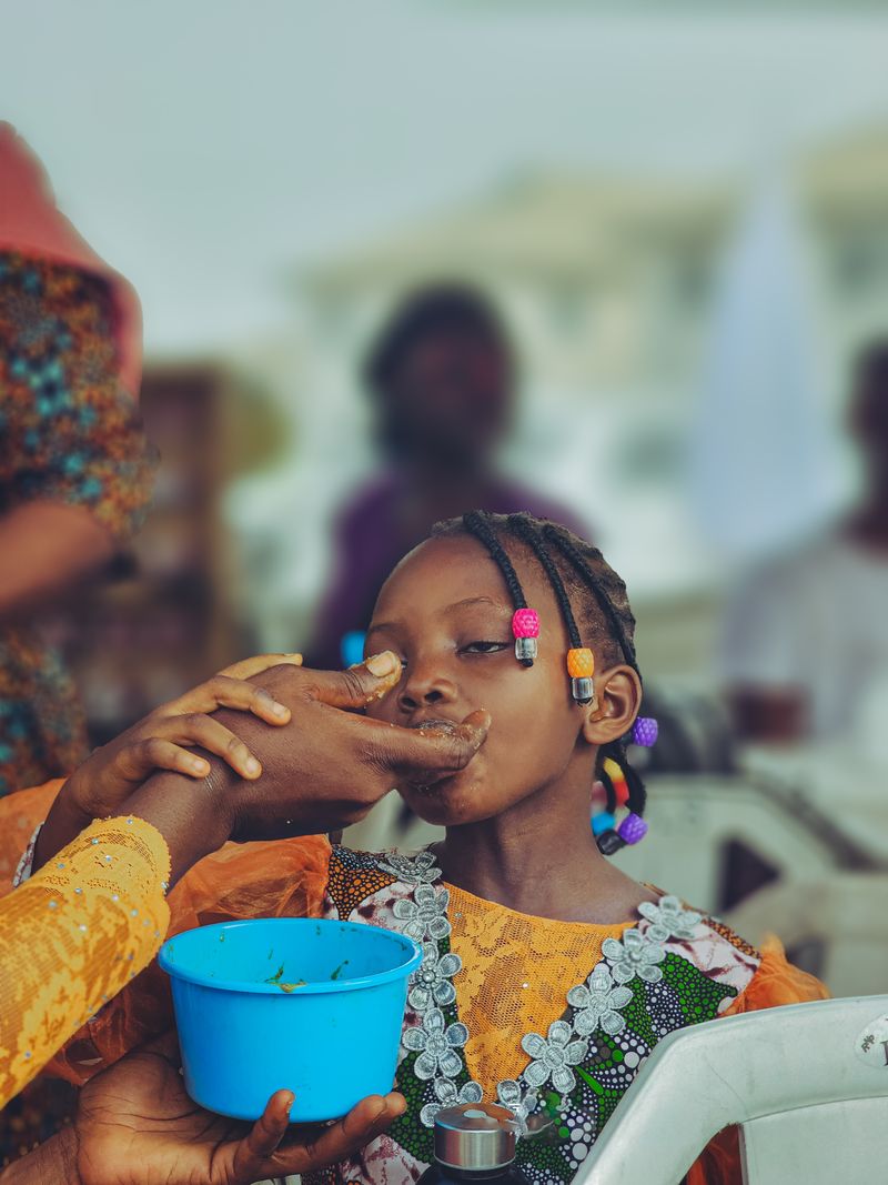 A young girl is fed a traditional meal